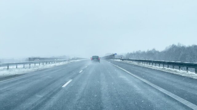 Driving a car during a snowstorm on the highway. Snow is visible on the road.
