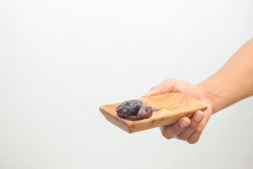 Hand holding a small wooden dish with a single dried plum
