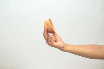 Hand holding empty ice cream cone against a white background