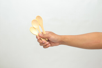 Hand Holding Three Wooden Spoons Against White Background
