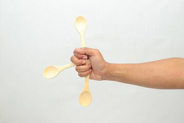 Hand Holding Wooden Spoons in Star Shape Against White Background