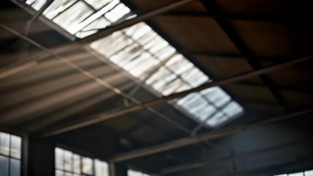 Closeup medium shot of natural skylight beams filtering through a warehouse ceiling the bright rays and window frame crisp against a softly blurred interior.