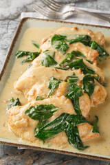 Chicken Florentine is a classic dish consisting of fried chicken fillet and spinach, served with a creamy sauce, close-up on a plate at the table. Vertical
