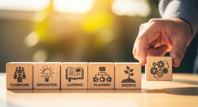 Hand arranging wooden blocks with business strategy icons in bright sunlight