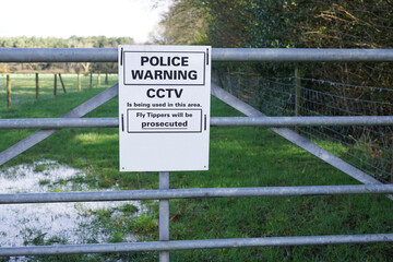 Fototapeta premium Police sign on a farm gate warning of the use of CCTV to combat fly tipping