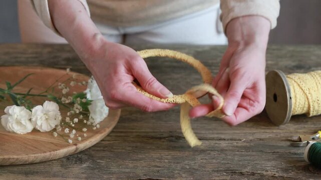 Florist at work: woman shows how to make small wreath with carnation flowers and gypsophila paniculata twigs. Step by step, tutorial. Images available.
