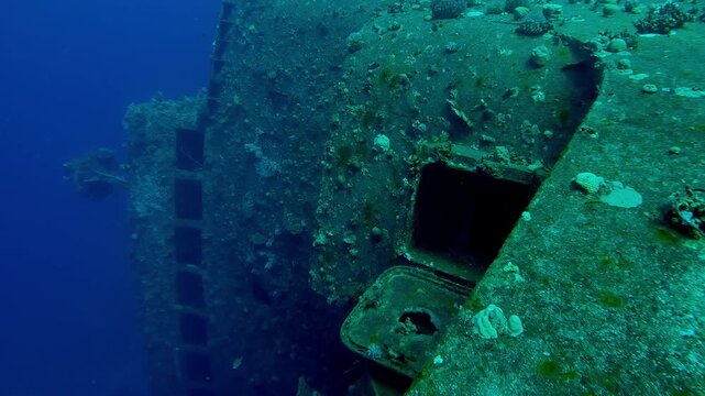 Approaching a corals-covered wheelhouse with windows of Salem Express ferry, Wreckship in Red Sea, Slow motion, Details of sunken ship in the depth sea