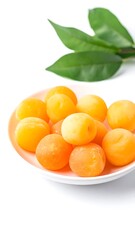 Apricots arranged in a pink bowl against a white background, accompanied by some green leaves