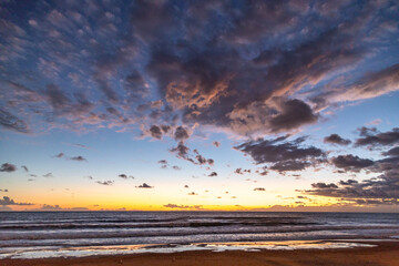 Obraz premium Panoramic afterglow sunset over the Mediterranean sea in Side. Dramatic twilight sky with scattered clouds and soft waves on the beach in Antalya region, Turkey. November, moody coastal vista.