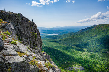 Wonderful view over the surrounding forest on a warm summer day, a lone determined hiker at the edge of the cliff, Charlevoix region, Quebec, Canada
