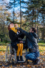 Fototapeta premium Woman in a wheelchair and her boyfriend together in a park