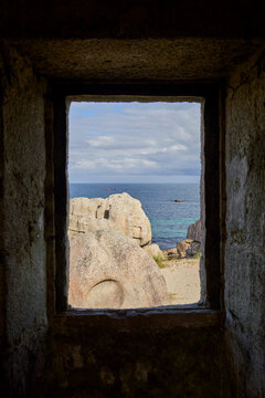 View through a window of the sea and rocks, with a blue sky and clouds. A peaceful and picturesque sight. France, Brittany, Plage des Amiets.