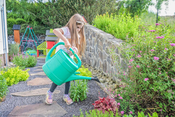 A young girl attentively fills a green watering can, focusing on gardening tasks with enthusiasm, portraying the joy of nurturing plants and understanding nature's beauty