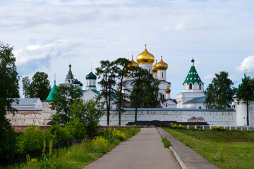 Golden domes of Orthodox monastery behind green trees