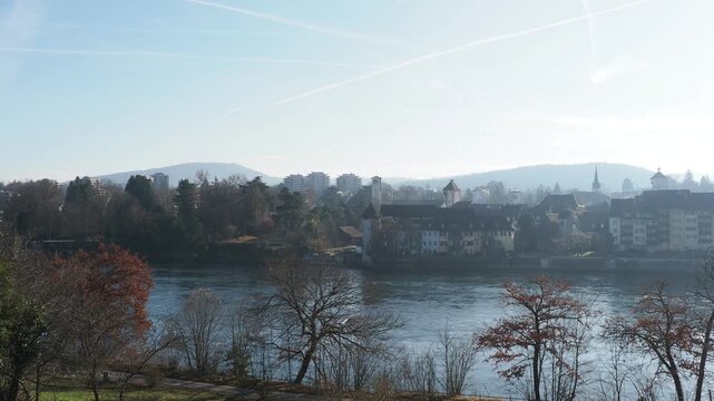 Rheinfelden (Aargau) in Switzerland, the medieval city seen in the mist from the Adelberg hill and its rows of trees on the right bank of the Rhine in Germany
