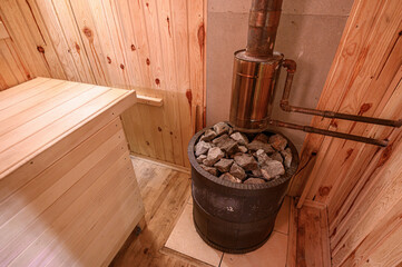 Wood-paneled sauna room with a metal stove topped with rocks, wooden bench, tiled base under stove, rustic design, warm ambiance, traditional setup.