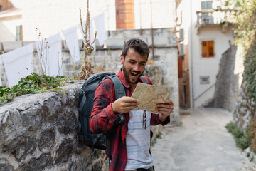 Young man with backpack and map exploring a historic old town