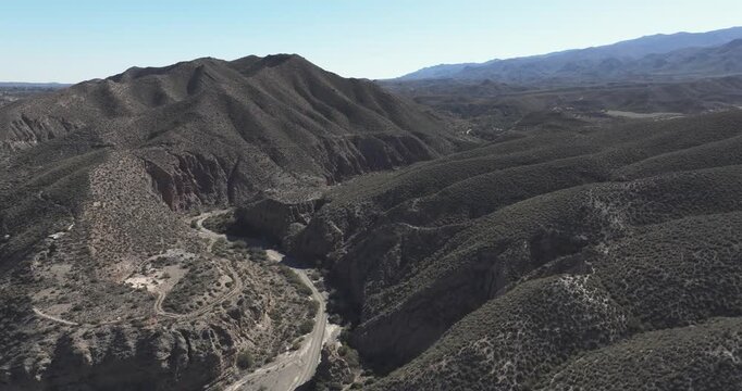 Tabernas Desert Spain aerial looking down a sinuous canyon and dry wash with layered hills and arid mountain ridges in Andalusia