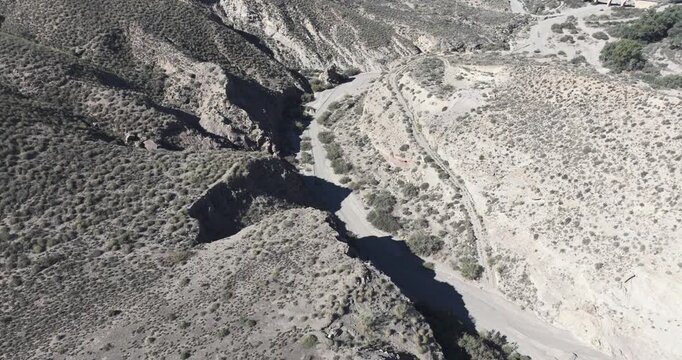 Top down drone view of Tabernas Desert dry river and canyon bend with stark erosion patterns and scrub in arid Spain