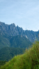 Fototapeta premium Many peaks Mount Kinabalu is highest tropical mountain in Borneo, jagged mountain peaks. Clouds hide in gorges. Geological rise of adolescent mountains continues. Landscape of once Mysterious Island