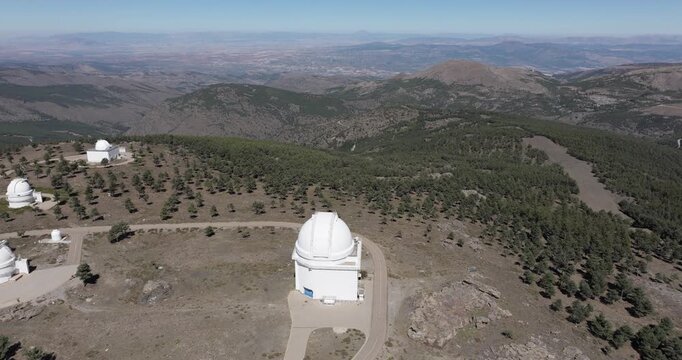 Calar Alto Observatory drone approach over mountain plateau with telescope domes and access roads in Spain astronomy research centre