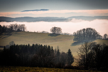 Neblige Landschaft im Querformat mit Sonnenstrahlen, Wiesen und Fichtenwald in Th&uuml;ringen