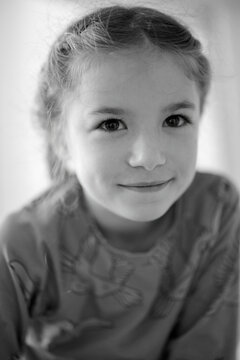 Young girl smiling softly in a cozy indoor setting with natural light