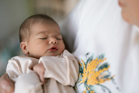 Newborn baby sleeping peacefully while being held close in a tender moment