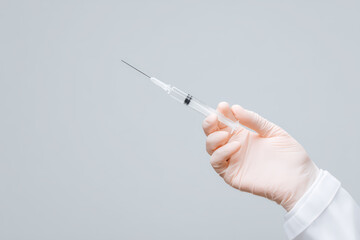 Syringe held by hand wearing medical glove with clear background, medical injection tool for healthcare and vaccination use, sterile and precise equipment