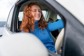 Naklejka premium Smiling woman drives a car with a focus on her joy and the outdoors in the background