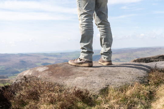 Hiker stands on rock ledge overlooking valley in late afternoon