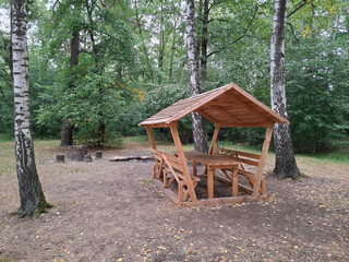 New wooden gazebo with a table for relaxing and dining in a forest park area