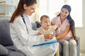 Fototapeta premium Pediatrician and baby play with stethoscope. At a relaxed home visit, the mother watches as the doctor encourages curiosity during a gentle healthcare checkup. Concept family-friendly care.