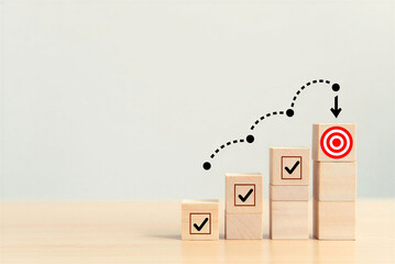 Wooden blocks with checkmarks and target symbol on a lightcolored wood surface with grey background  business concept