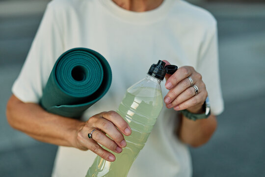 Portrait of a middle aged mature beautiful sport woman smiling happy and confident. Standing and  doing exercise and stretching and holding a bottle of water or energy drink or juice during a break in