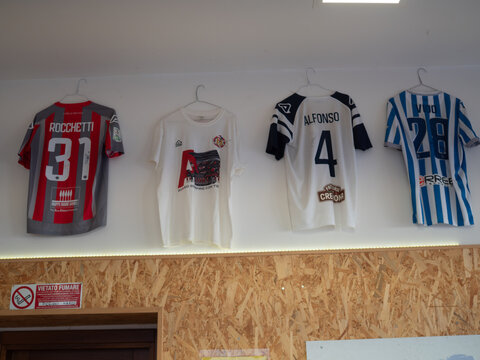 Italian soccer jerseys hanging on wall, featuring historic Serie A and B teams, celebrating football passion and fan culture