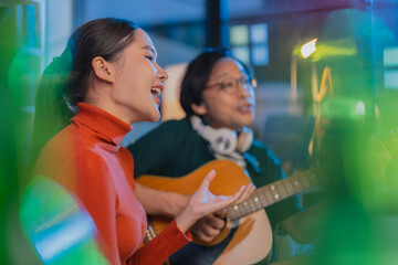 alented Asian musician and singer host a live stream concert from home at night, using a ring light for a professional online broadcast and influencer experience