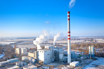Industrial power plant smokestack with steam emissions in winter landscape, RDF energy production concept