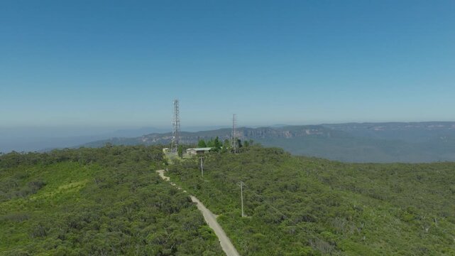 Drone aerial footage flying towards and over telecommunication towers on the ridgeline of the Jamison Valley in the Blue Mountains in New South Wales, Australia.