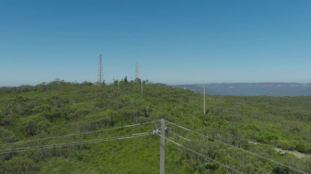Drone aerial footage flying towards and over telecommunication towers on the ridgeline of the Jamison Valley in the Blue Mountains in New South Wales, Australia.