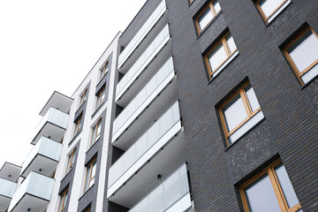 Modern apartment building exterior with balconies. Low angle view of residential architecture. Urban housing facade detail. New real estate development. City living concept with copy space. © Paweł Michałowski