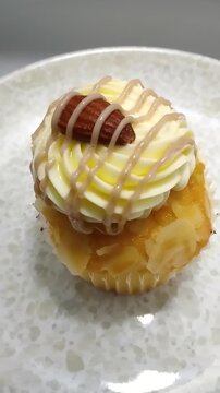 High Angle Vertical Video of a Salted Caramel Drizzle Cupcake with Buttercream and Almond Garnish Spinning on a Plate