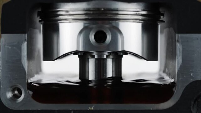 Close up slow motion view of engine pistons interacting with oil inside a cylinder block