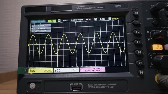A digital oscilloscope screen displays a yellow sine wave as the camera pans right, revealing the instrument's controls. Concept of signal analysis, electronic measurement, and engineering.