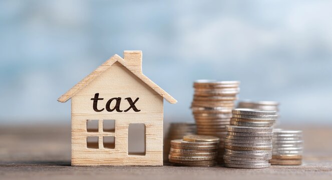 Property tax concept with wooden house and stacks of coins