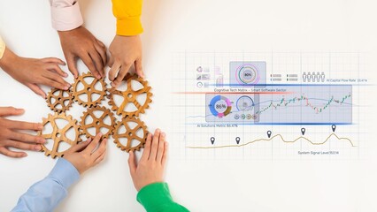 A group of diverse hands gathers around wooden gears on a white table, highlighting teamwork and collaboration, alongside data analytics graphs for business success. Raster