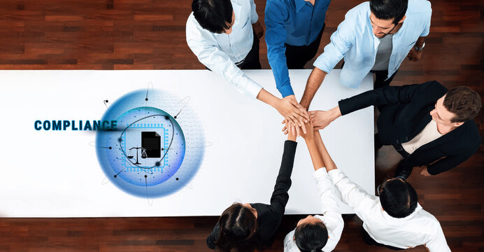 A diverse team collaborates around a table, emphasizing unity and compliance. Hands come together to symbolize teamwork and commitment to shared objectives in a corporate setting. Trope