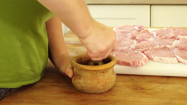 Woman grinding spices for meat in a wooden mortar