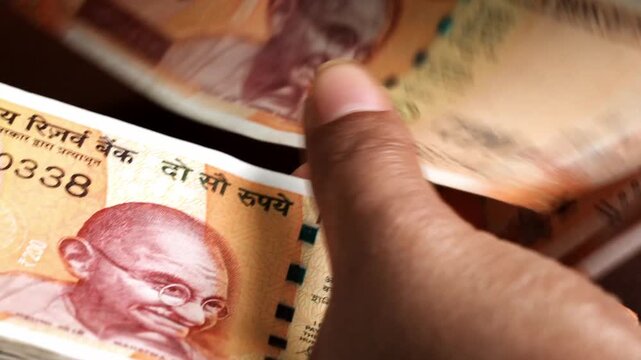Close-up of hands counting Indian ₹200 currency notes, reflecting everyday cash handling, personal finance management, and the role of physical money in household expenses and debt repayment