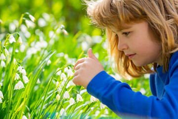 Spring mood with happy child. Kid with white flowers, outdoor profile portrait. Child daydreaming in spring field. Cute face of child. Dreamy kid in spring garden. Kid smelling spring snowflake. © Volodymyr